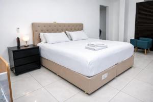 a bedroom with a large bed with white sheets and a table at Quitinete inteligente Centro da Cidade Unidade 1 in Presidente Prudente