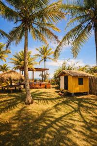 a small shack and palm trees in a field at Varanda do Mar Caraíva Oceanfront in Porto Seguro