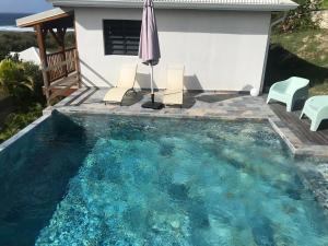 a swimming pool with an umbrella and chairs and a house at Sukha Lodge in Le Moule +3 photos