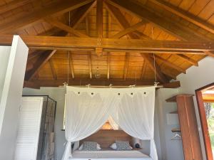 a room with a bed with a white curtain at Sukha Lodge in Le Moule