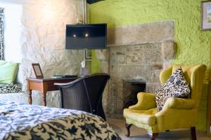 a bedroom with a bed and a chair and a fireplace at The Oxenham Arms Hotel Devon in South Zeal