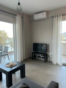 a living room with a tv and a table at Serene beach house in Diakopto