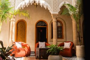 a lobby with two chairs and a table and palm trees at Riad Golden in Rabat