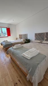 a room with three beds with towels on them at Quinta Maria Cotovia in Porto Covo