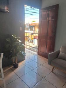 a living room with a door and a chair and a plant at Quepos Explorers Hub Spacious Apartment in Quepos