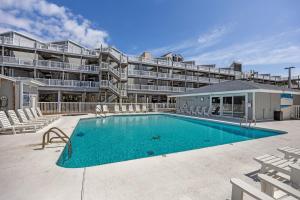 a swimming pool in front of a large building at Tranquility By The Sea-Oceanside Condo in Salter Path