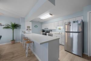 a kitchen with white cabinets and a refrigerator at Tranquility By The Sea-Oceanside Condo in Salter Path