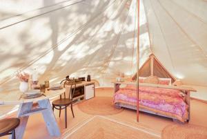 a bedroom in a tent with a bed and a desk at Reflections Byron Bay - Holiday Park in Byron Bay