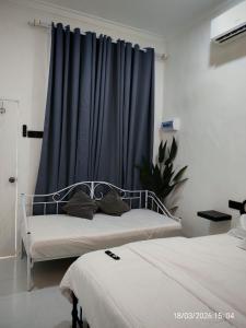 a bedroom with two beds and a blue curtain at Zaifaa Beach Inn in Setiu
