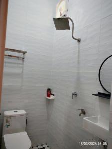 a bathroom with a toilet and a sink and a light at Zaifaa Beach Inn in Setiu