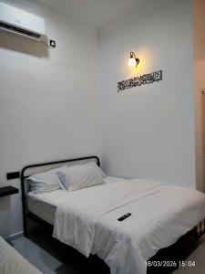 a bedroom with a bed and a light on the wall at Zaifaa Beach Inn in Setiu