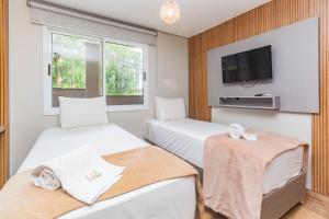 a hotel room with two beds and a tv at Hotel Morada Del Este in Canoas