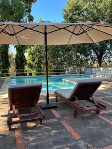 two chairs under an umbrella next to a swimming pool at Atlakamani Surf in Chirilagua