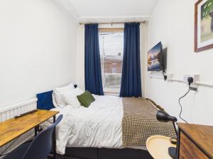 a bedroom with a bed and a desk and a window at Parkview Guest House in King's Lynn