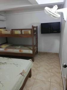 a room with two bunk beds and a flat screen tv at Casa madrigueña rincón del mar in Rincón