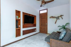 a living room with a couch and a flat screen tv at Private Jungle Villa with Full Kitchen & Pool Access in Tulum