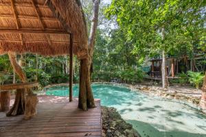 a resort with a swimming pool with a thatched roof at Private Jungle Villa with Full Kitchen & Pool Access in Tulum