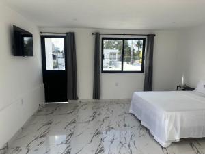 a white bedroom with a bed and two windows at Casa Dorada in Cancún