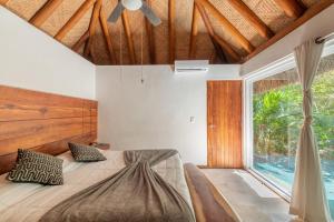 a bedroom with a bed and a large window at Luxury Jungle Suite with Private Jacuzzi & Cenote Pool View in Chemuyil