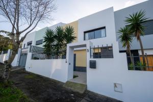 a white house with palm trees in front of it at A casa da Girafa in Ponta Delgada