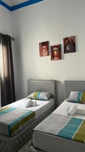 two beds in a bedroom with pictures on the wall at maison bleu hajja in Tangier