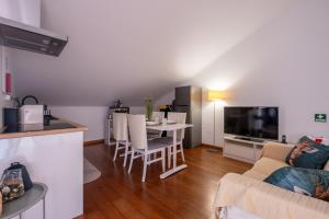 a kitchen and a living room with a table and a tv at A casa da Girafa in Ponta Delgada