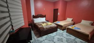 a room with two beds and a chair and red walls at Casa de Lewis in San Cristóbal