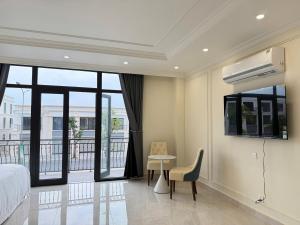a bedroom with a bed and a desk and a balcony at Na homes coffee in Binh Hai