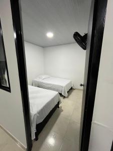 two beds in a small room with a doorway at El Rincon de Teresita in Villavicencio