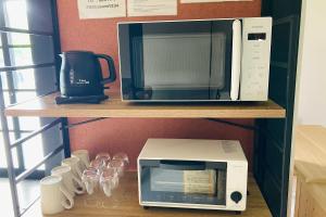 a microwave and a coffee maker and glasses on a shelf at あざみ庵 奄美大島 in Amami