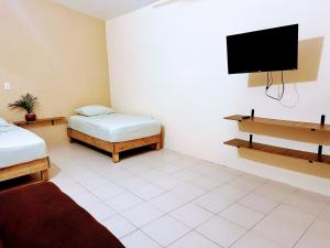 a room with two beds and a flat screen tv at Casa Brisas in Puerto Escondido