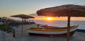 a boat sitting under an umbrella next to the ocean at Hotel Salinas São Jorge in São Filipe +5 photos
