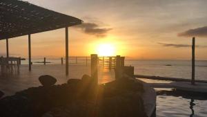 a sunset over the ocean with people sitting on a pier at Hotel Salinas São Jorge in São Filipe