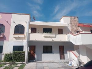 a white building with brown doors on the side of it at Comfortable, bright and compact in Tembladera