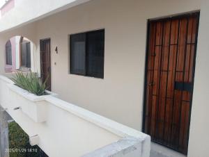 a house with a wooden door and a staircase at Comfortable, bright and compact in Tembladera