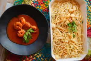 a bowl of food with shrimp and spaghetti next to a container at Vivá Barra Hotel Pousada in Barra de São Miguel