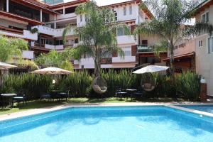 a swimming pool in front of a building with tables and umbrellas at Hotel Tierras Blancas in Valle de Bravo