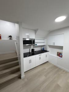 a kitchen with white cabinets and a black sink at Granite Grove Suite in Winnipeg