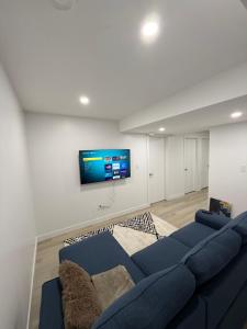 a living room with a blue couch and a flat screen tv at Granite Grove Suite in Winnipeg