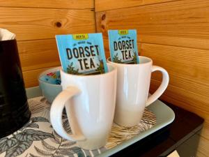 two coffee cups sitting on a tray with books on them at Glebe Summer House in Osmington