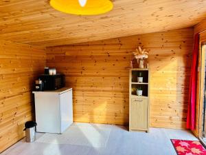 a room with a wooden wall with a refrigerator and a shelf at Glebe Summer House in Osmington