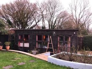 a small black tiny house in a garden at Glebe Summer House in Osmington +6 photos