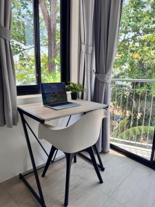 a laptop computer sitting on a desk in front of a window at Phuket Muay Thai Hotel Rawai Beach in Rawai Beach
