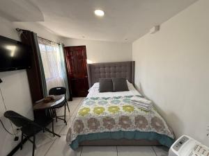 a bedroom with a bed and a table and a television at Alojamiento Cereza 1 WiFi in Alajuela