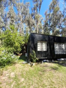 a black tiny house in a field with trees at La Chaira in Santa Ana +4 photos