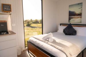 a bedroom with a bed with a large window at The Nest at Arahura Escape by Tiny Away in Kaihinu