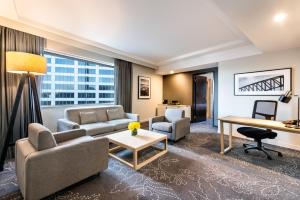 a living room with a couch and a desk at PARKROYAL Darling Harbour, Sydney in Sydney