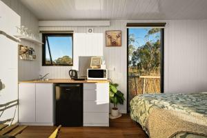 a bedroom with a bed and a desk with a microwave at Rivergum Lodge by Tiny Away in Scotts Creek
