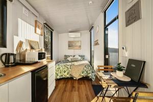 a bedroom in a tiny house with a bed and a desk at Rivergum Lodge by Tiny Away in Scotts Creek