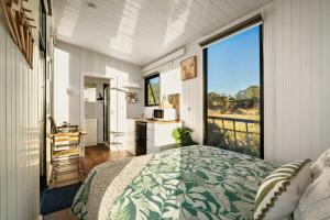 a bedroom with a bed and a large window at Rivergum Lodge by Tiny Away in Scotts Creek
